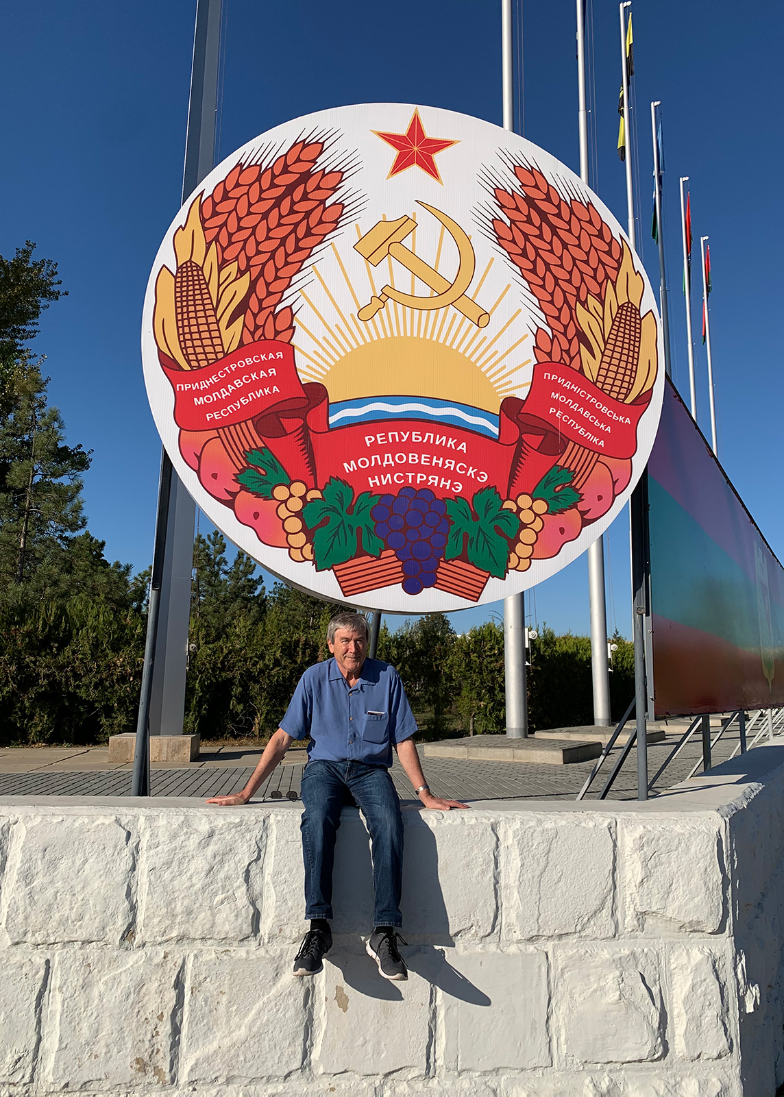 Paul Davies sits in front of a colorful sign for a the post-soviet breakaway state of Transnistria