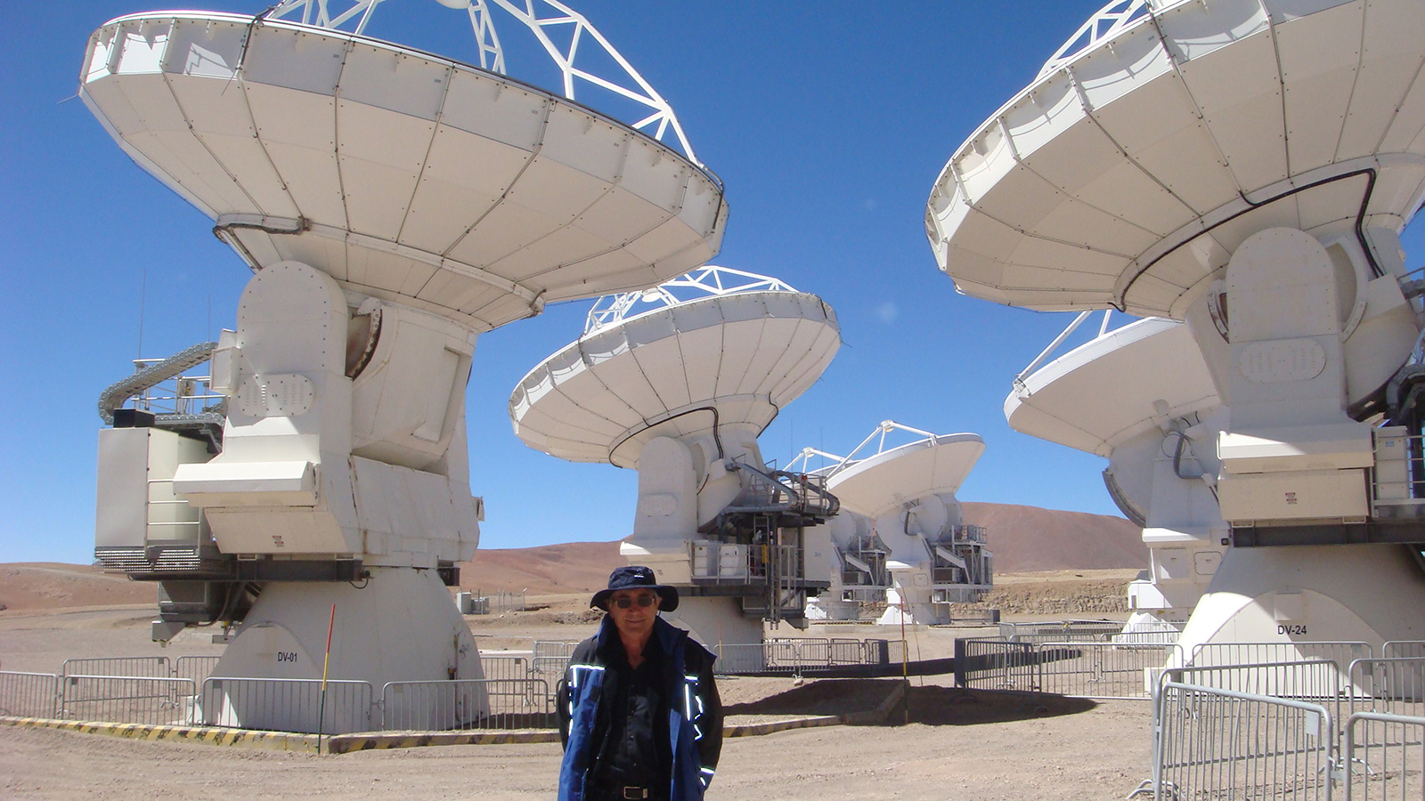Paul Davies standing in front of an array of telescope antennas